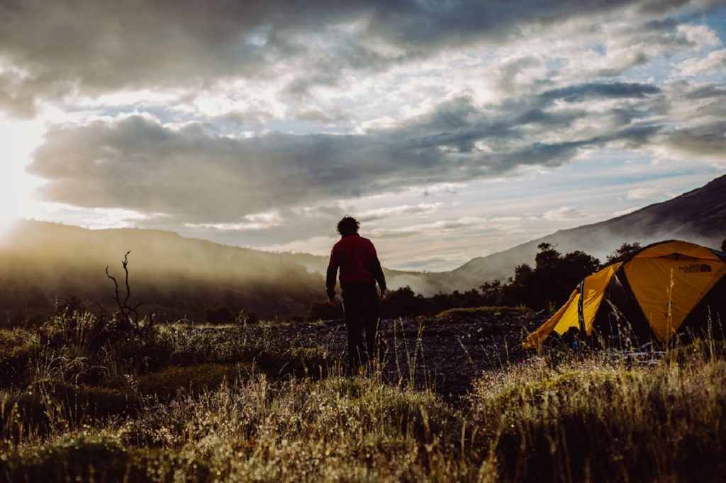 Abbildung zeigt Person mit Zelt Camping mit Sport und Outdoor Equipment in den Bergen